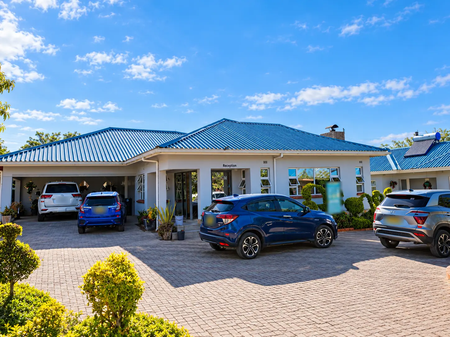 The reception building at Castle Base Lodge, with a blue roof and a paved forecourt