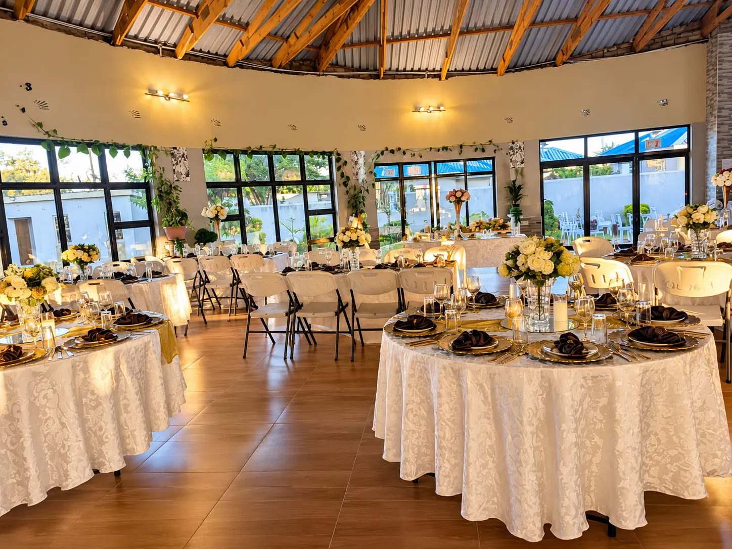 Round banquet tables dressed in white damask with flowers and place settings in the function hall