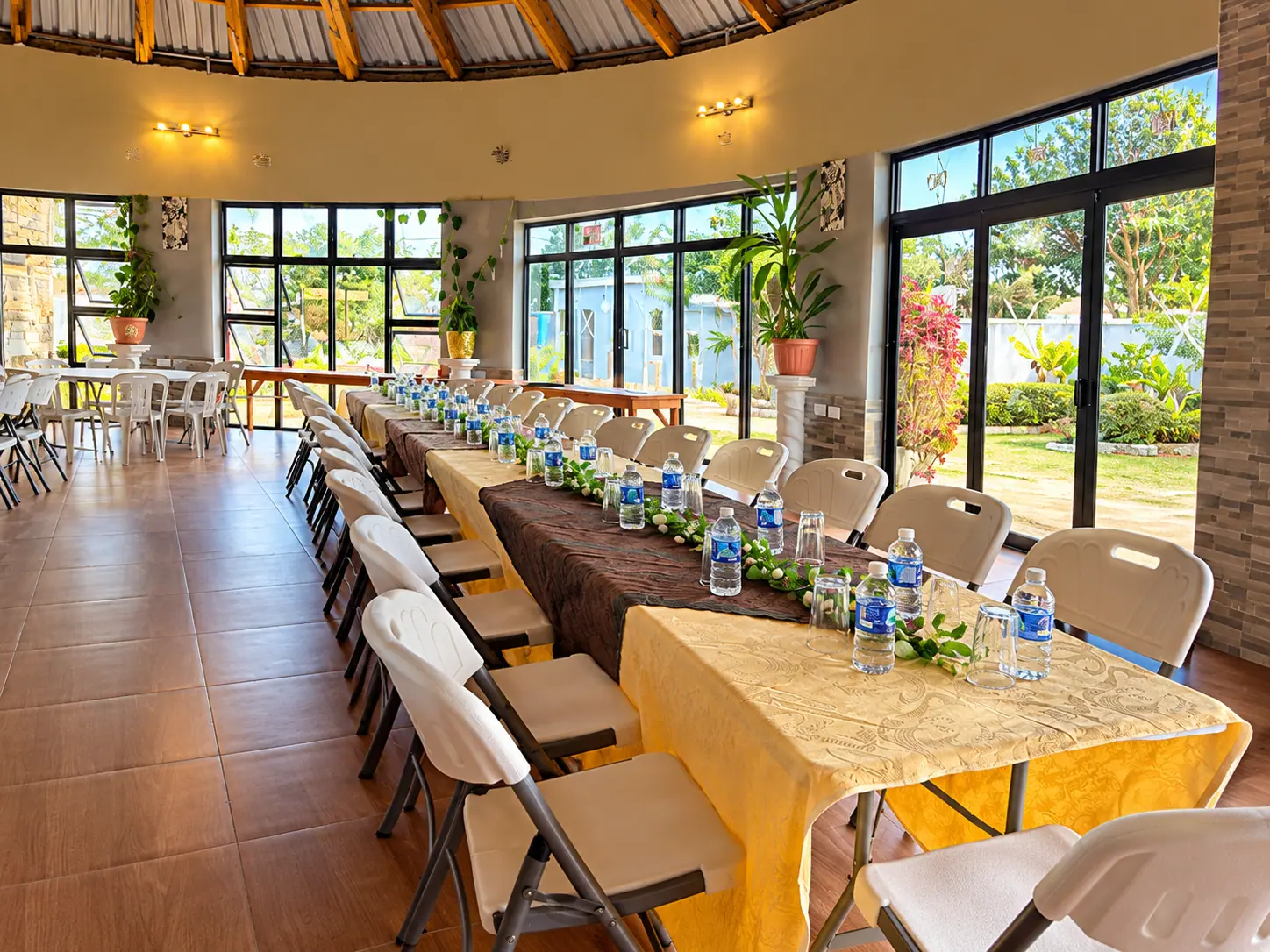 A long conference table with gold cloths, water bottles and white chairs in the bright hall